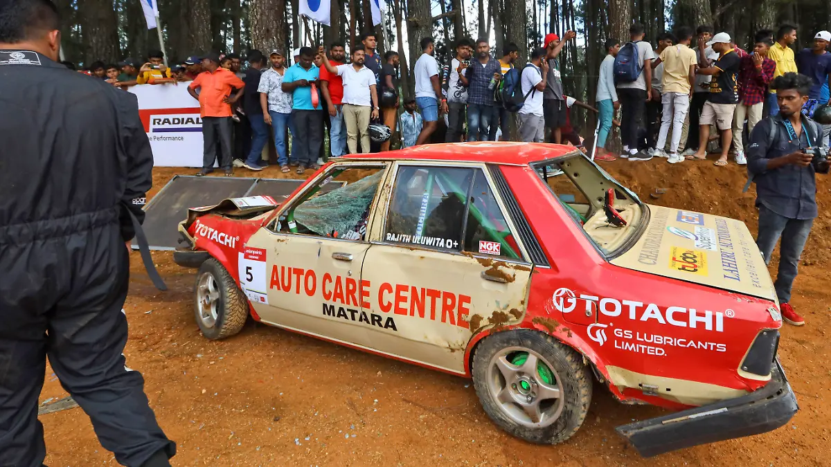 People gather around a car that had crashed into the spectators during the Fox Hill Supercross, a  motor racing event organized by the Sri Lanka's army, in Diyatalawa, Sri Lanka, Sunday, April 21, 2024. (AP Photo/STR)