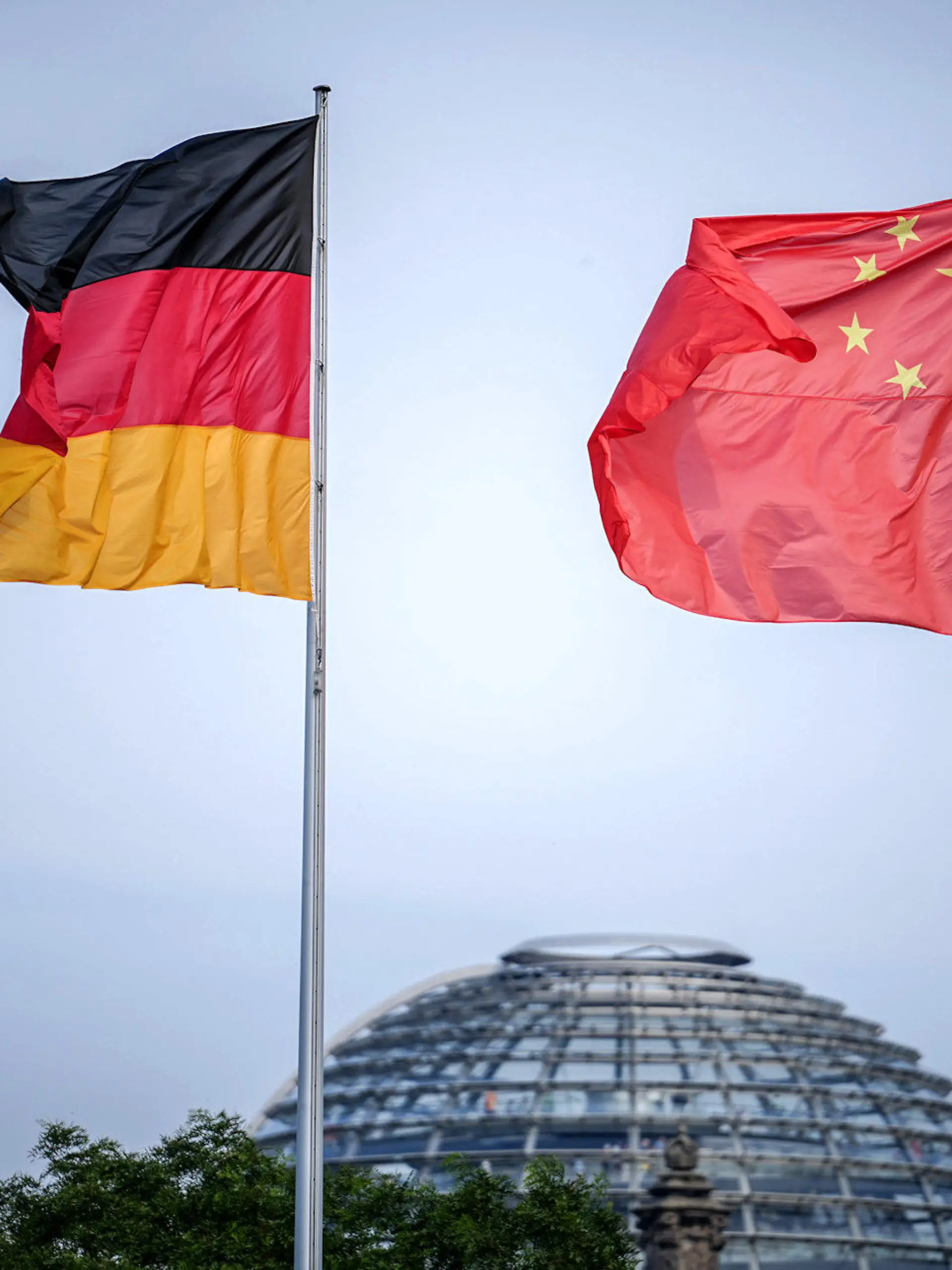 ARCHIV - 19.06.2023, Berlin: Die Flaggen von Deutschland und China wehen zum Auftakt des Deutschland-Besuchs der chinesischen Regierung im Wind vor dem Bundeskanzleramt, im Hintergrund die Kuppel des Reichstagsgebäudes. (zu "Drei Deutsche wegen mutmaßlicher Spionage für China festgenommen") Foto: Kay Nietfeld/dpa +++ dpa-Bildfunk +++