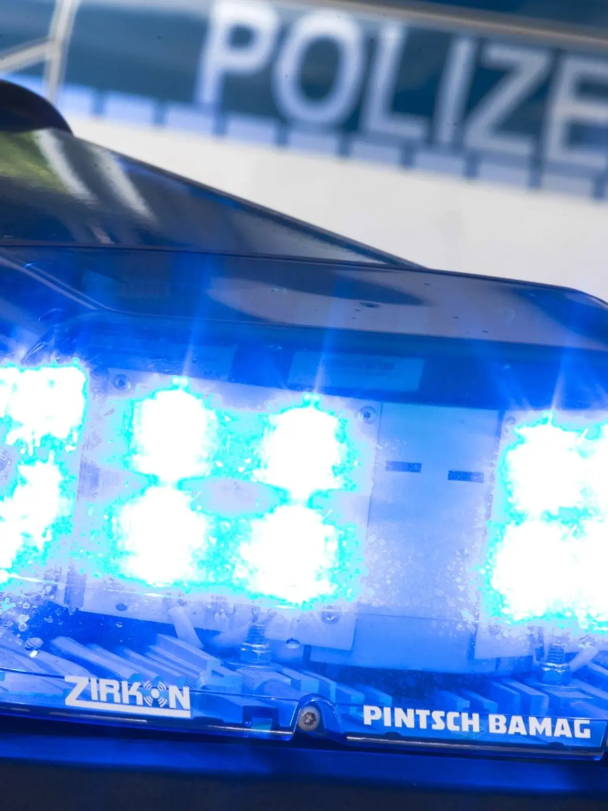 Ein Blaulicht leuchtet während eines Einsatzes auf dem Dach eines Polizeiwagens.