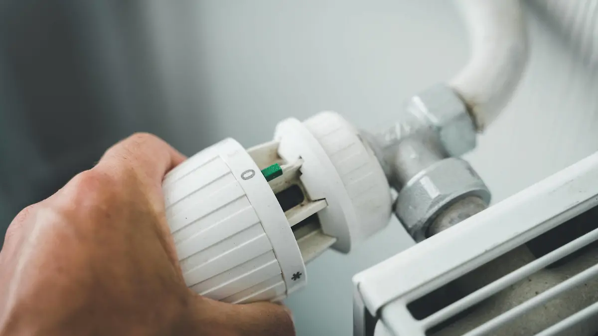 29 July 2022: male hand turns heating thermostat to zero to save electricity, gas and heating costs, hand regulates radiator *** männliche Hand dreht das Thermostat der Heizung auf Null um Strom, Gas und Heizkosten zu Sparen, Hand reguliert Heizkörper