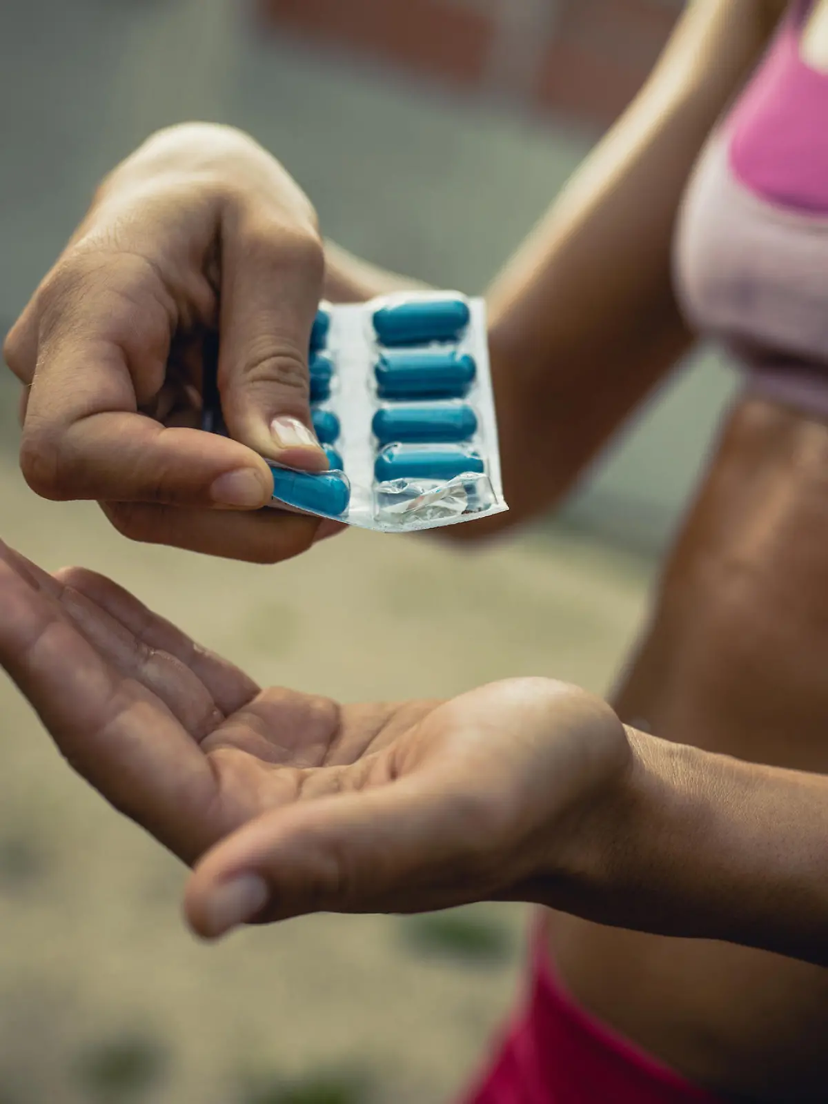 Close up of unrecognizable female athlete taking pills before sports training.