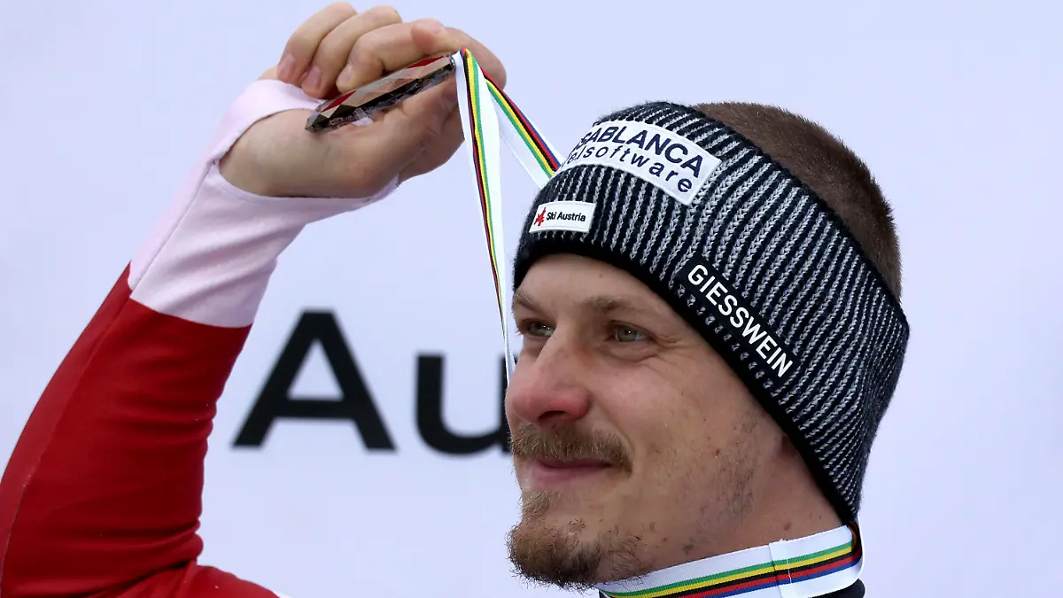 Austria's Manuel Feller holds up the bronze medal for his third place in the alpine ski World Cup overall standings, in Saalbach, Austria, Sunday, March 24, 2024. (AP Photo/Marco Trovati)