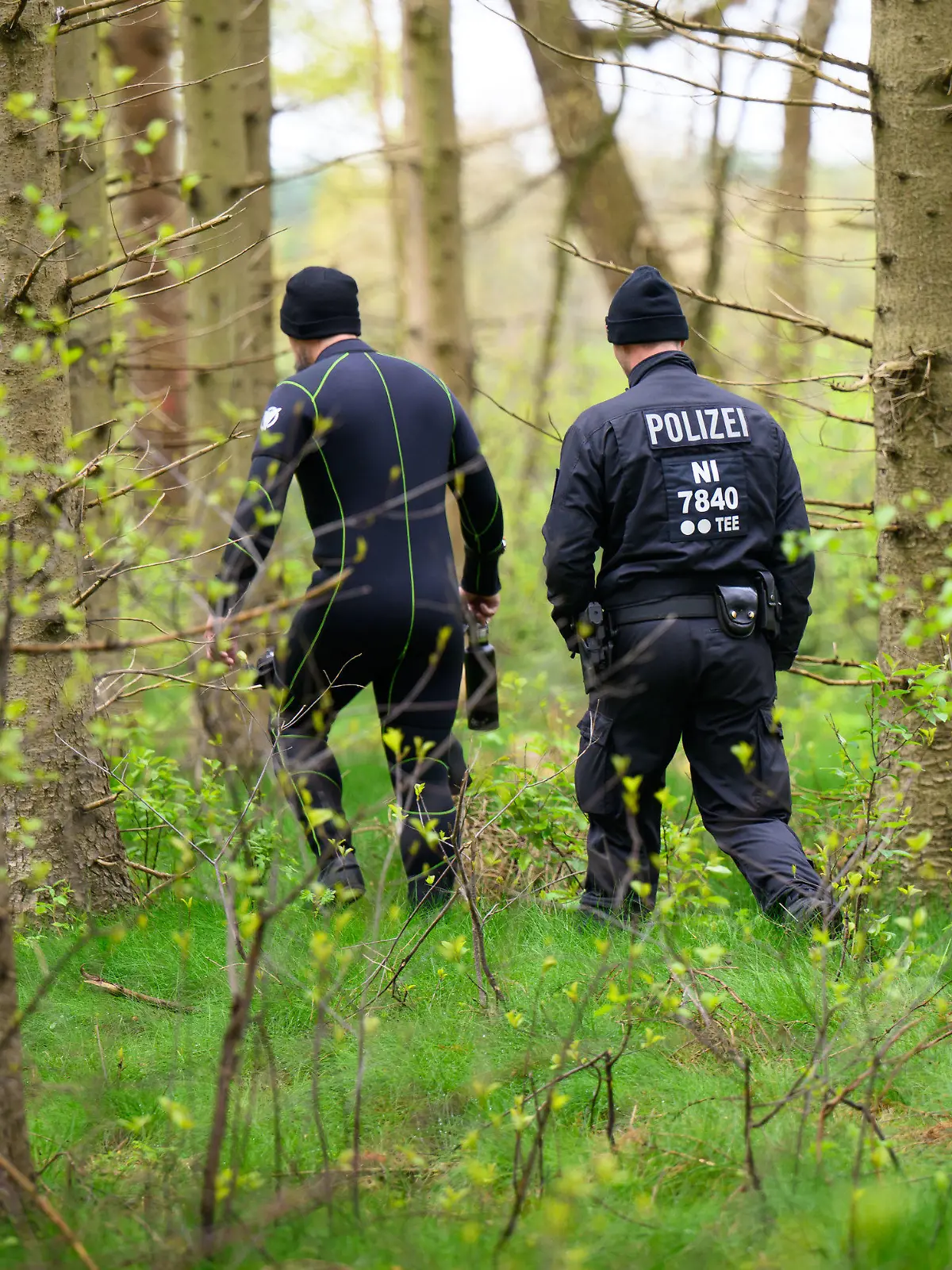 24.04.2024, Niedersachsen, Behrste: Eine Tauchereinheit der Polizei geht durch ein Waldstück. Von dem vermissten sechs Jahre alten Jungen aus dem niedersächsischen Bremervörde fehlt noch immer jede Spur. Foto: Daniel Reinhardt/dpa +++ dpa-Bildfunk +++