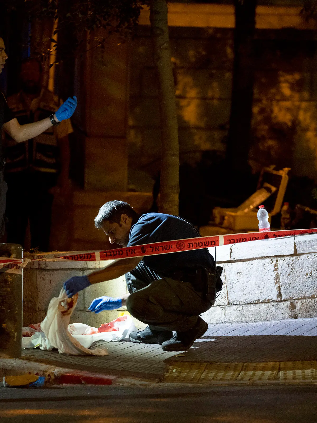 Israeli police crime scene investigators work at the scene of a shooting attack that wounded several Israelis near the Old City of Jerusalem, early Sunday, Aug. 14, 2022. Israeli police and medics say a gunman opened fire at a bus in a suspected Palestinian attack that came a week after violence flared up between Israel and militants in Gaza. (AP Photo/ Maya Alleruzzo)