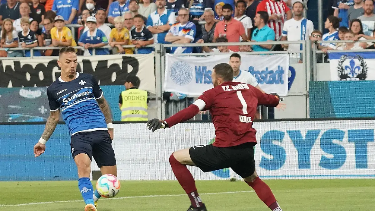 13.08.2022, Hessen, Darmstadt: Fußball, 2. Bundesliga, 4. Spieltag, SV Darmstadt 98 - Hansa Rostock, Merck-Stadion am Böllenfalltor. Phillip Tietz (l) von Darmstadt erzielt das Tor zum 1:0 gegen Rostocks Torwart Markus Kolke. Foto: Hasan Bratic/dpa - WICHTIGER HINWEIS: Gemäß den Vorgaben der DFL Deutsche Fußball Liga bzw. des DFB Deutscher Fußball-Bund ist es untersagt, in dem Stadion und/oder vom Spiel angefertigte Fotoaufnahmen in Form von Sequenzbildern und/oder videoähnlichen Fotostrecken zu verwerten bzw. verwerten zu lassen. +++ dpa-Bildfunk +++