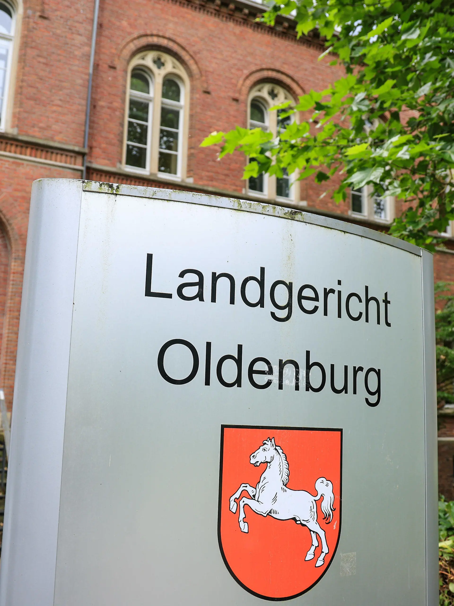 19.07.2023, Niedersachsen, Westerstede: Ein Schild vor dem Landgericht Oldenburg, in dem ein Berufungsverfahren im Fall eines Bestatters beginnt. Der Angeklagte soll zwischen 2016 und 2019 mehrere Urnen bewusst mit anderer Asche, Staub oder Dreck befüllt und beigesetzt haben. Das Amtsgericht verurteilte ihn in einem ersten Verfahren wegen Anstiftung zur Störung der Totenruhe zu einer Bewährungsstrafe von acht Monaten und einer Geldstrafe von 5000 Euro an ein Hospiz. Dagegen ging der Bestatter in Berufung und der Prozess wird vor dem Landgericht Oldenburg neu verhandelt. Foto: Focke Strangmann/dpa +++ dpa-Bildfunk +++