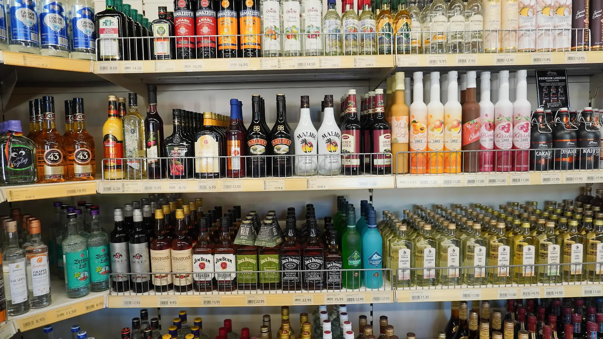 Zahlreiche Getränke mit Alkohol stehen fein säuberlich aufgereiht in einem Supermarkt.