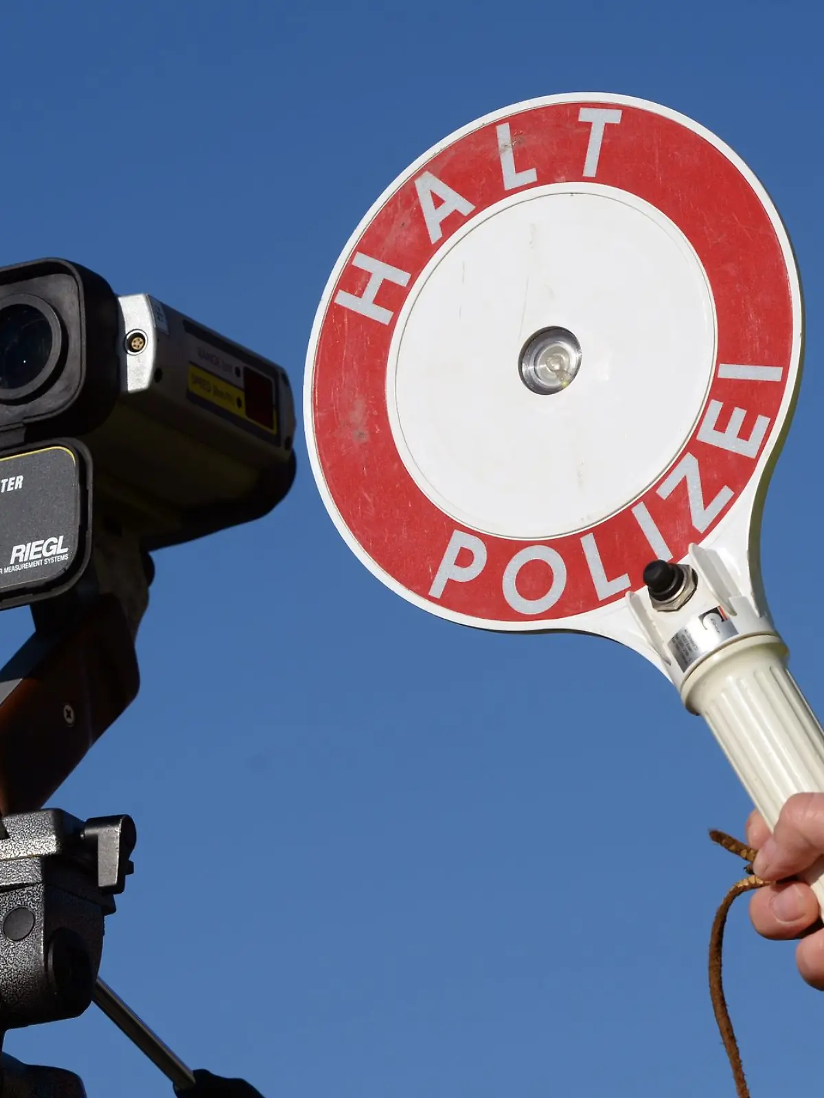 Ein Polizist hält in Kleinmachnow (Brandenburg) eine Anhaltekelle neben einem Geschwindigkeitsmessgerät.