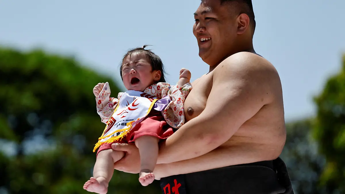 A baby cries while held up by amateur sumo wrestlers during 'Nakizumo' or a baby-crying sumo contest, where two wrestlers hold a baby each and a referee makes faces and loud noises to make them cry and determines the winner based on the loudest baby, at Sensoji temple in Tokyo, Japan, April 28, 2024. The ritual is believed to aid the healthy growth of the children and ward off evil spirits. REUTERS/Issei Kato