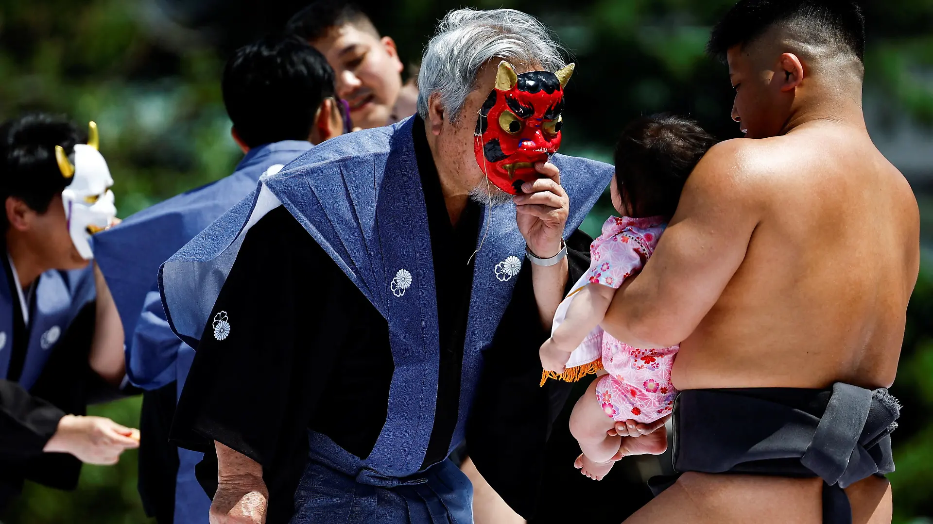Ring assistants wear masks to scare babies held up by amateur sumo wrestlers during 'Nakizumo' or a baby-crying sumo contest, where two wrestlers hold a baby each and a referee makes faces and loud noises to make them cry and determines the winner based on the loudest baby, at Sensoji temple in Tokyo, Japan, April 28, 2024. The ritual is believed to aid the healthy growth of the children and ward off evil spirits. REUTERS/Issei Kato