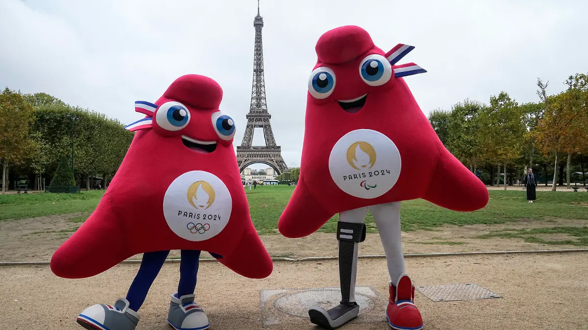 ARCHIV - 28.08.2023, Frankreich, Paris: Die Maskottchen der Olympischen (l) und Paralympischen Spiele Paris 2024 stehen vor dem Eiffelturm. (zu dpa: «Frankreich um maximale Sicherheit für Olympia in Paris bemüht») Foto: Michel Euler/AP/dpa +++ dpa-Bildfunk +++