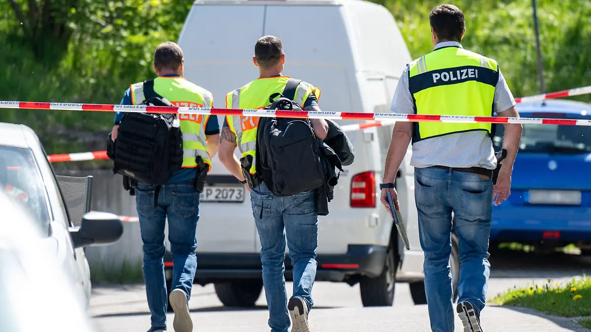 29.04.2024, Bayern, Bodenmais: Polizeibeamte gehen hinter Absperrbändern zu einem Parkplatz. Mit mehreren Schüssen soll ein Mann eine 47 Jahre alte Frau auf einem Parkplatz lebensgefährlich verletzt haben. Der tatverdächtige 61-Jährige habe sich später selbst getötet, teilte die Polizei mit. Foto: Armin Weigel/dpa +++ dpa-Bildfunk +++