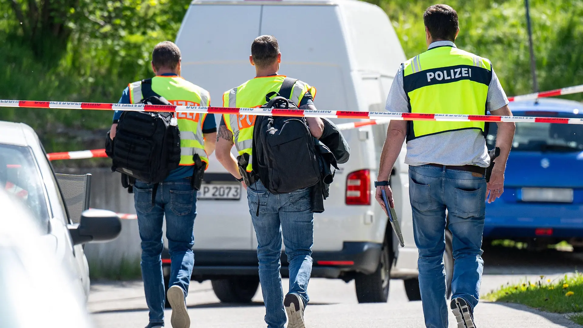 29.04.2024, Bayern, Bodenmais: Polizeibeamte gehen hinter Absperrbändern zu einem Parkplatz. Mit mehreren Schüssen soll ein Mann eine 47 Jahre alte Frau auf einem Parkplatz lebensgefährlich verletzt haben. Der tatverdächtige 61-Jährige habe sich später selbst getötet, teilte die Polizei mit. Foto: Armin Weigel/dpa +++ dpa-Bildfunk +++