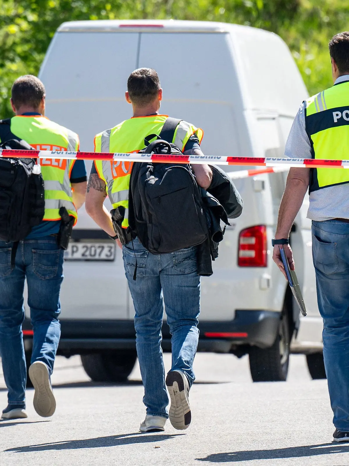 29.04.2024, Bayern, Bodenmais: Polizeibeamte gehen hinter Absperrbändern zu einem Parkplatz. Mit mehreren Schüssen soll ein Mann eine 47 Jahre alte Frau auf einem Parkplatz lebensgefährlich verletzt haben. Der tatverdächtige 61-Jährige habe sich später selbst getötet, teilte die Polizei mit. Foto: Armin Weigel/dpa +++ dpa-Bildfunk +++