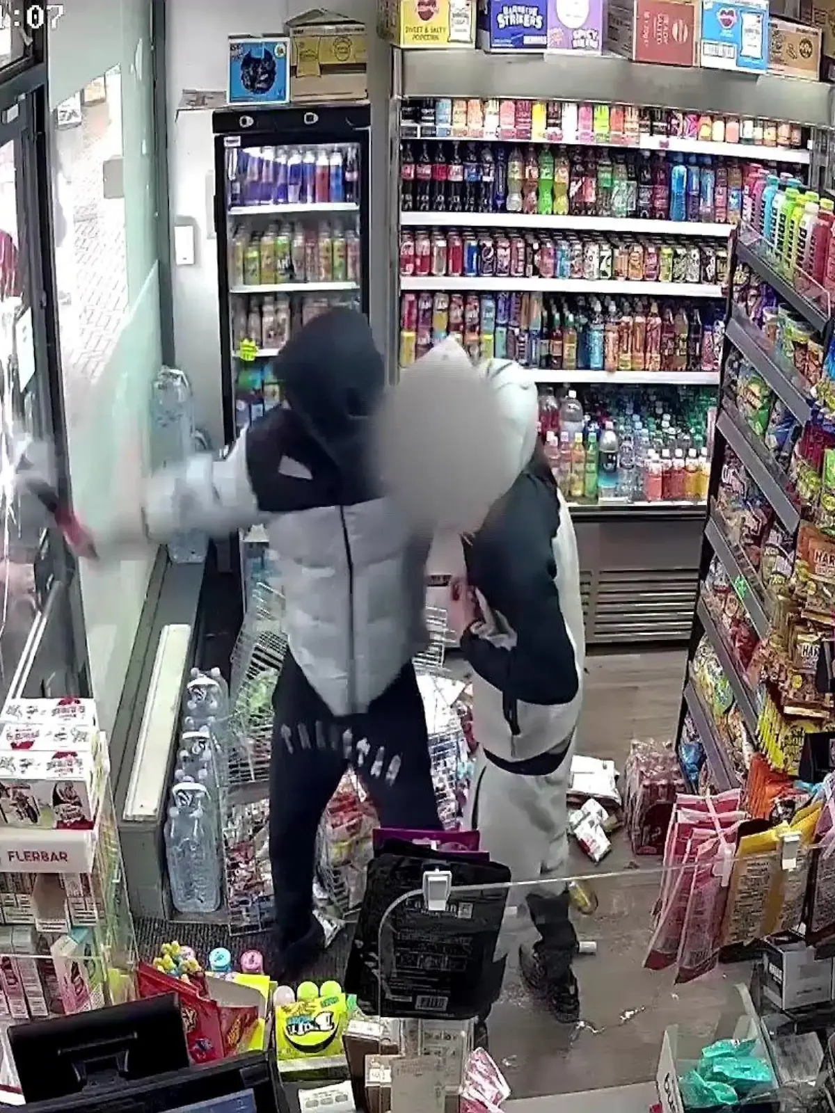 Ein junger Mann schlägt mit einer Machete auf eine Glastür ein.