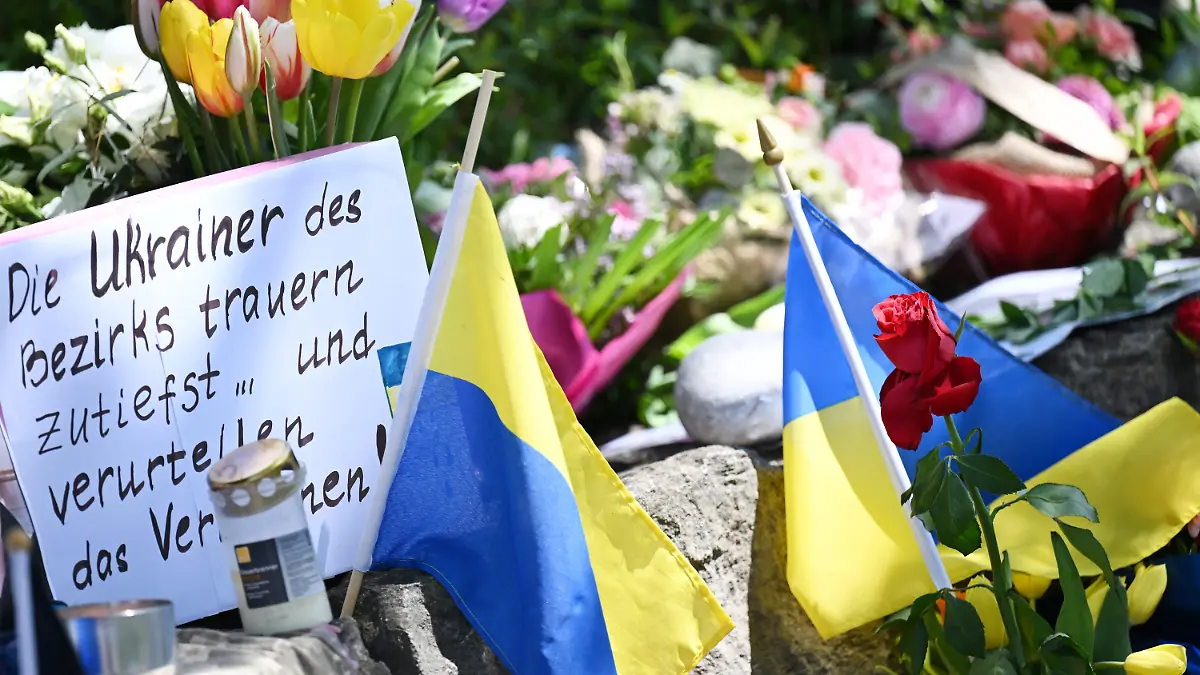 dpatopbilder - 29.04.2024, Murnau Am Staffelsee: Neben dem Einkaufszentrums an dem am Samstagabend zwei Männer aus der Ukraine getötet worden sind, haben Menschen Blumen und Plakate niedergelegt. Die beiden getötete Ukrainer waren Armeeangehörige. Foto: Angelika Warmuth/dpa +++ dpa-Bildfunk +++