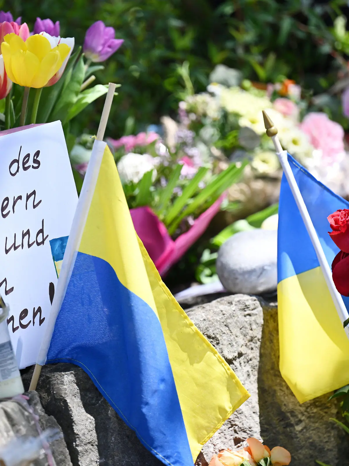 dpatopbilder - 29.04.2024, Murnau Am Staffelsee: Neben dem Einkaufszentrums an dem am Samstagabend zwei Männer aus der Ukraine getötet worden sind, haben Menschen Blumen und Plakate niedergelegt. Die beiden getötete Ukrainer waren Armeeangehörige. Foto: Angelika Warmuth/dpa +++ dpa-Bildfunk +++