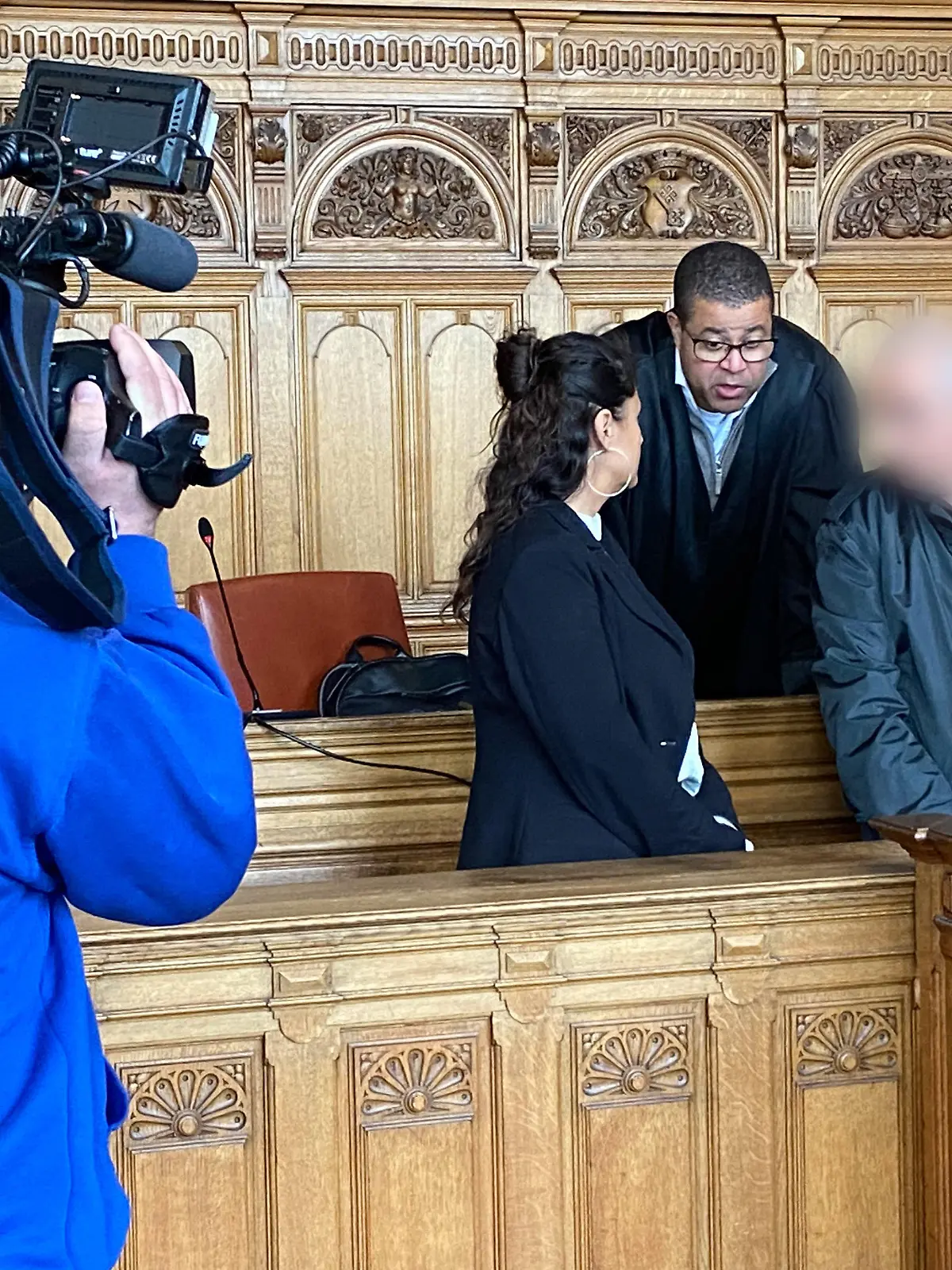 29.04.2024, Bremen: Der Angeklagte (r) steht vor Beginn des Prozesses mit seinem Anwalt Temba Hoch (hinten) und einer Dolmetscherin im Gerichtssaal im Landgericht Bremen. Er ist zu 13 Jahren Haft und Maßregelvollzug wegen Mordes an seinem siebenjährigen Sohn verurteilt worden. Foto: Janet Binder/dpa - ACHTUNG: Angeklagter wurde auf Anweisung des Gerichts aus rechtlichen Gründen gepixelt +++ dpa-Bildfunk +++