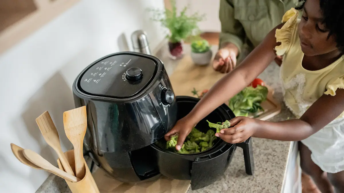 Mother teaching daughter how to prepare vegetables in an oil-free fryer