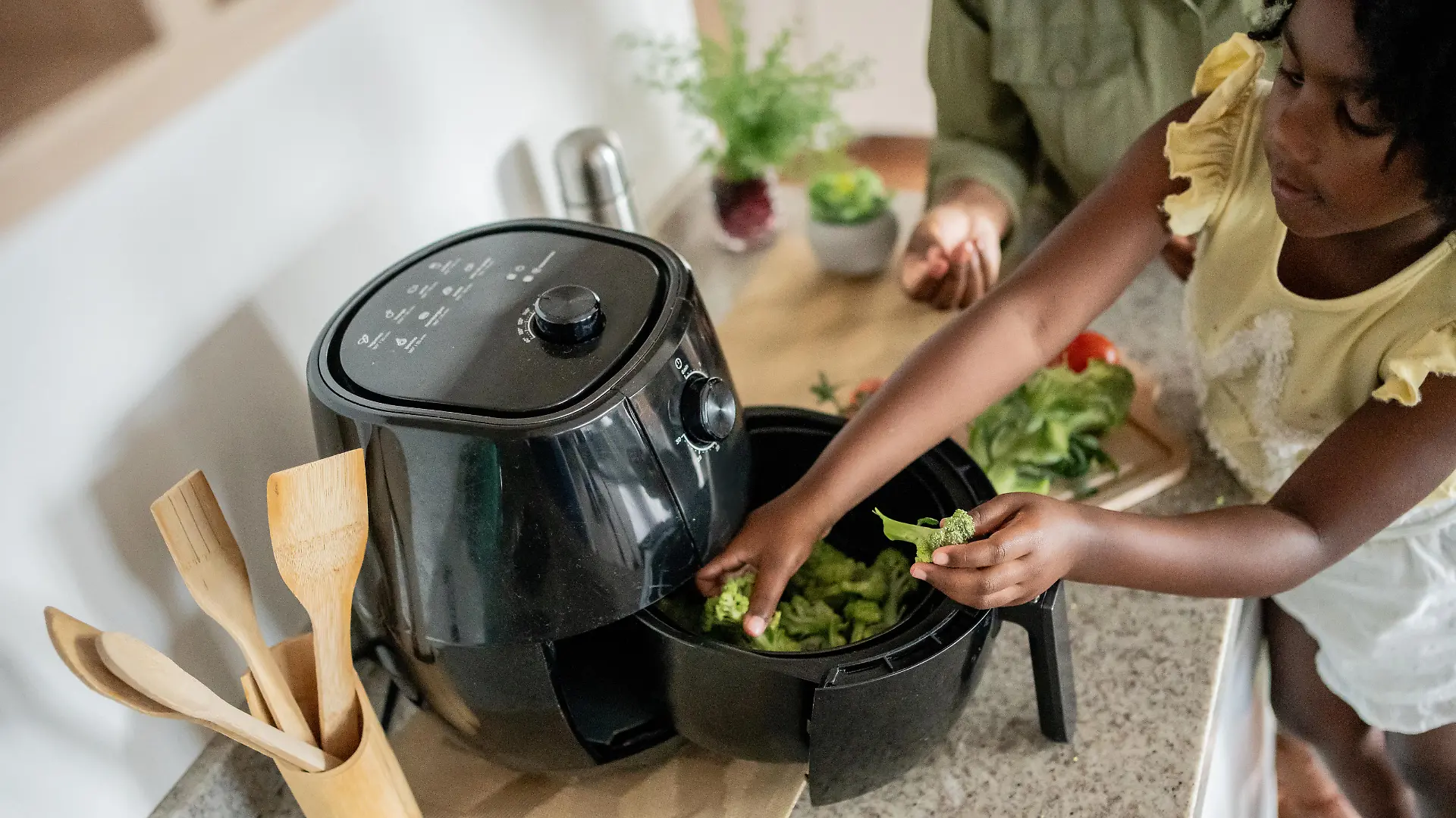 Mother teaching daughter how to prepare vegetables in an oil-free fryer