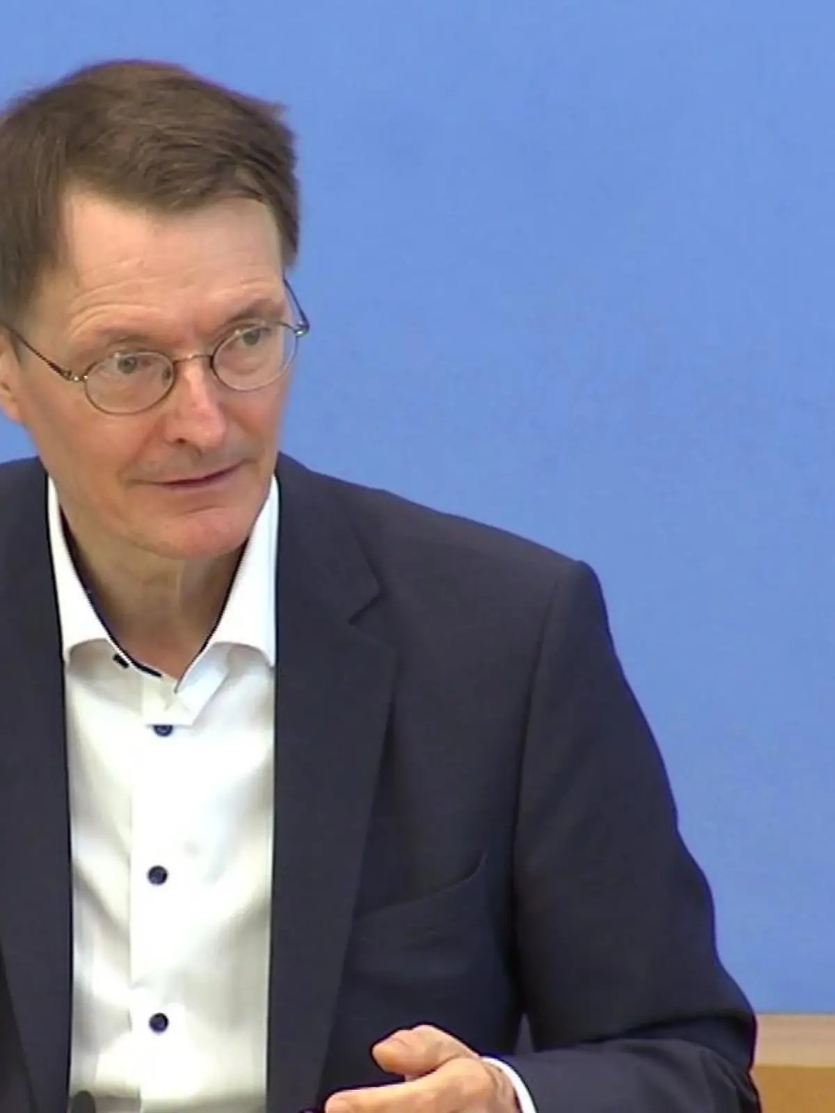 Während einer Pressekonferenz hält Karl Lauterbach sein digitales Impfzertifikat in die Kamera.