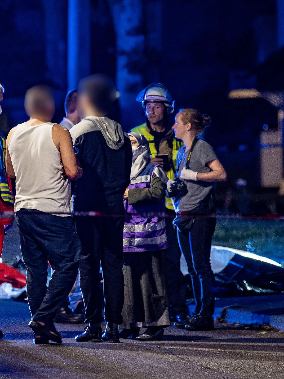 10.08.2022, Nordrhein-Westfalen, Solingen: Eine muslimische Notfallseelsorgerin trifft am Tatort ein und redet mit einem verletzten Mann. Ein 31 Jahre alter Mann ist bei einer Messerstecherei am Mittwochabend in Solingen tödlich verletzt worden. Trotz Reanimationsversuchen durch die Einsatzkräfte sei der Mann am Tatort gestorben, teilte eine Polizeisprecherin mit. Mindestens zwei weitere Personen seien ebenfalls verletzt worden. Ein männlicher Tatverdächtiger wurde am Tatort festgenommen. Genauere Angaben zu den Hintergründen der Tat machte die Polizei bislang nicht. Die Mordkommission hat die Ermittlungen aufgenommen. Foto: Christoph Reichwein/dpa +++ dpa-Bildfunk +++