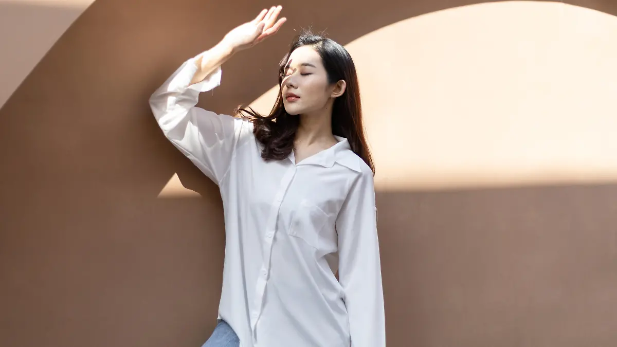 Portrait of a beautiful Asian woman with healthy skin. She uses a sun protection hand that hits her face to protect against UV that has caused her face to dull.