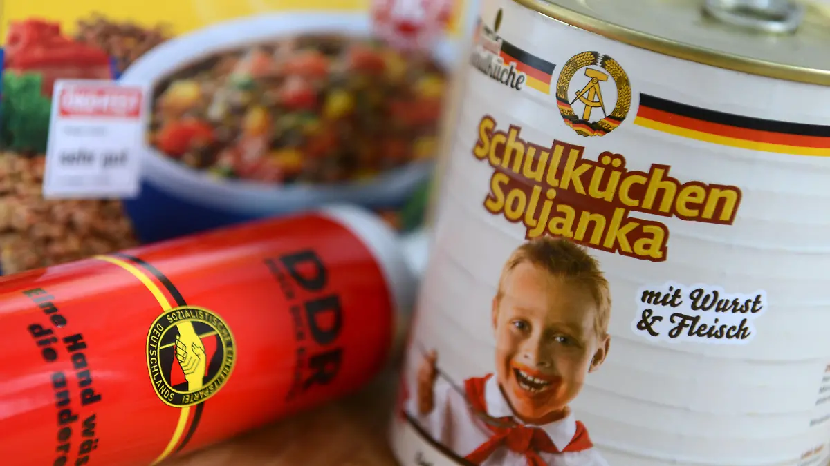 Eine Verpackung mit Linsen, ein Duschbad mit dem Parteilogo der SED und eine Soljanka mit DDR-Emblem und Thälmann-Pionier stehen am 18.03.2014 auf einem Tisch in Leipzig (Sachsen). Fast 25 Jahre nach dem Mauerfall sind "Ostprodukte" sowie der Verkauf von DDR-Resten wieder in den Fokus gerückt. Vor allem geht es um die Frage wo endet Nostalgie, wo beginnt Geschichtsklitterung? Foto: Hendrik Schmidt/dpa (zu dpa-KORR «DDR-Nostalgie in Dosen: Tomatensoße mit Pionierbild» vom 18.03.2014) ++