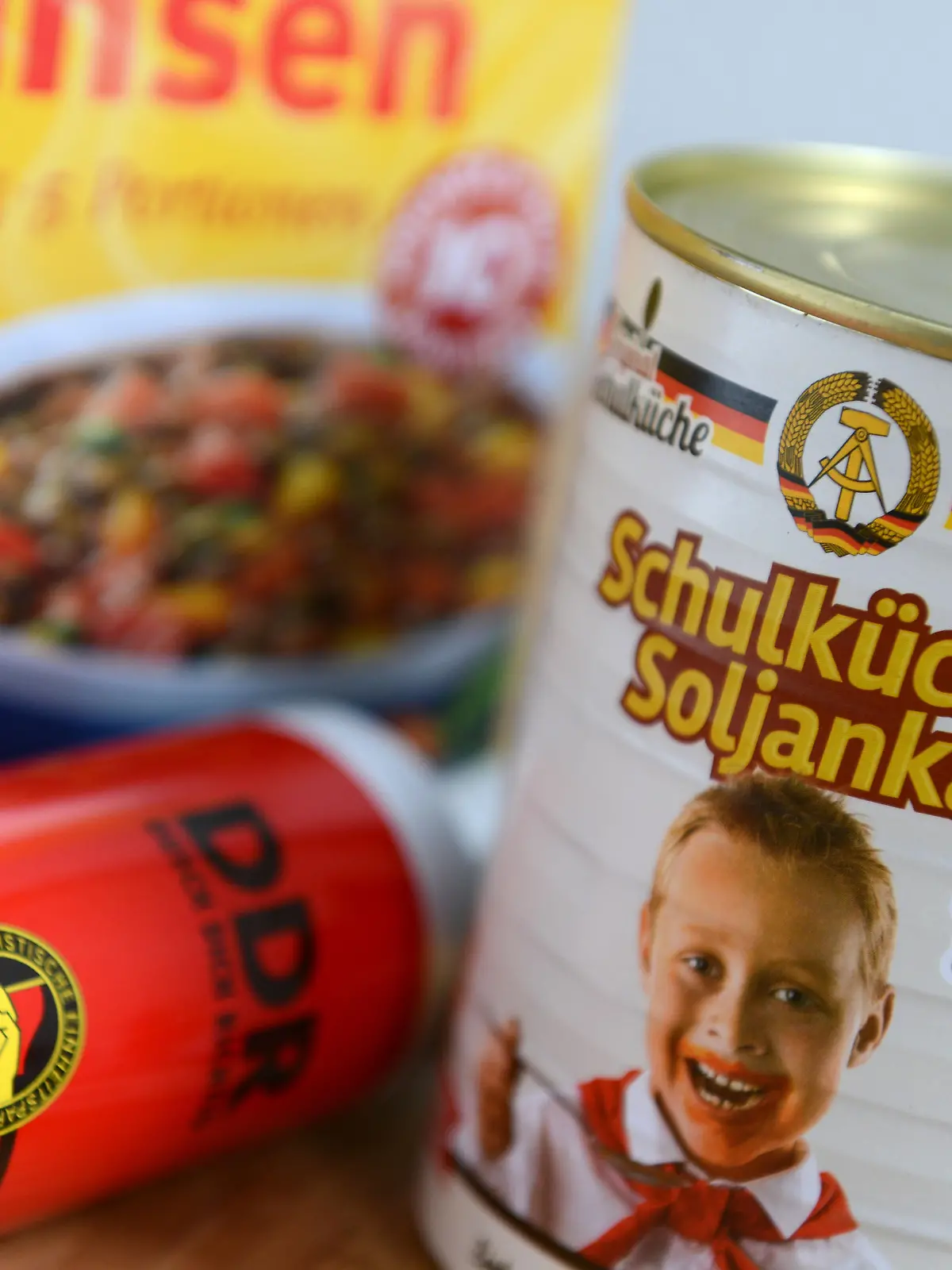 Eine Verpackung mit Linsen, ein Duschbad mit dem Parteilogo der SED und eine Soljanka mit DDR-Emblem und Thälmann-Pionier stehen am 18.03.2014 auf einem Tisch in Leipzig (Sachsen). Fast 25 Jahre nach dem Mauerfall sind "Ostprodukte" sowie der Verkauf von DDR-Resten wieder in den Fokus gerückt. Vor allem geht es um die Frage wo endet Nostalgie, wo beginnt Geschichtsklitterung? Foto: Hendrik Schmidt/dpa (zu dpa-KORR «DDR-Nostalgie in Dosen: Tomatensoße mit Pionierbild» vom 18.03.2014) ++