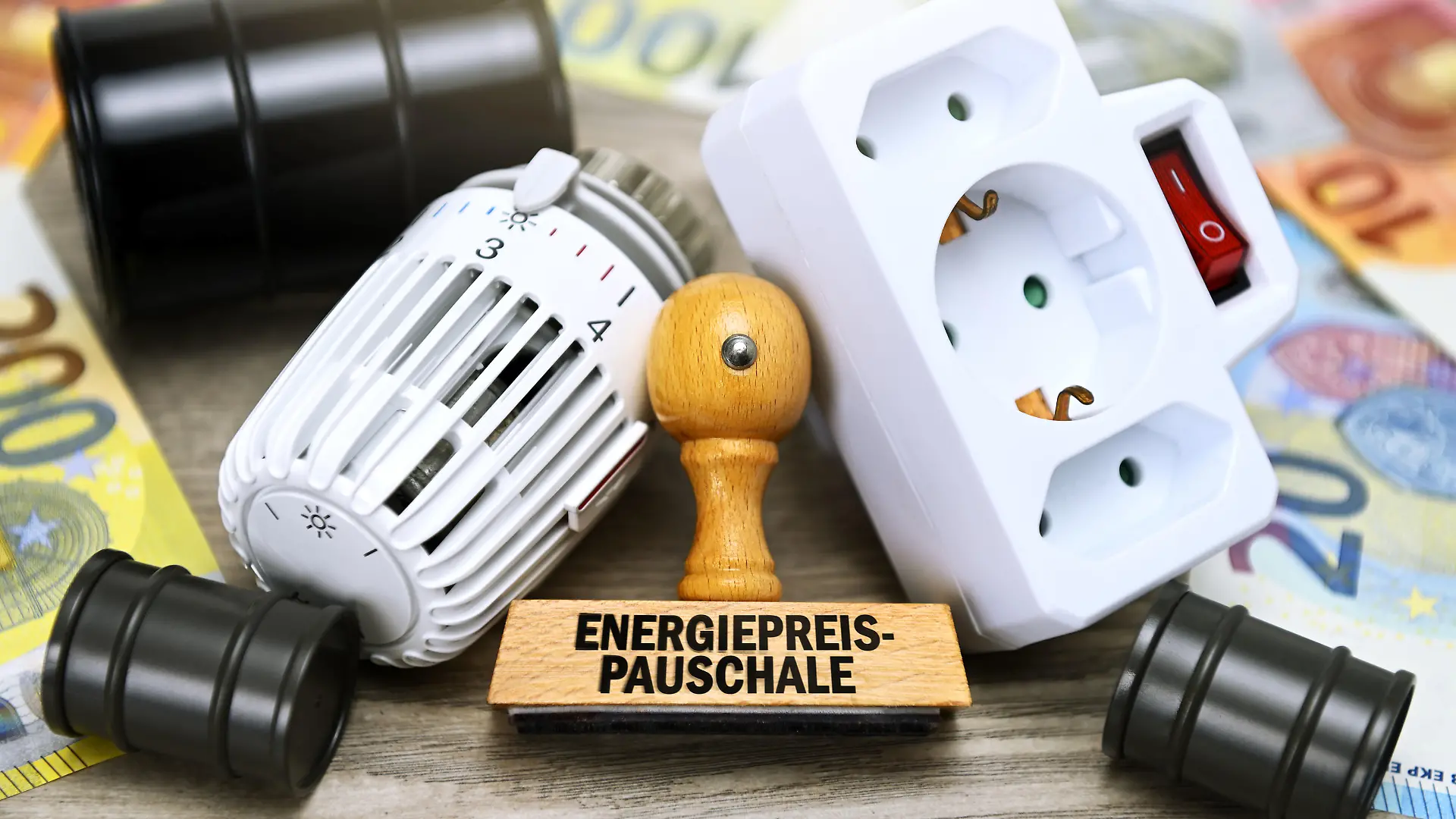 Stempel mit Aufschrift Energiepreispauschale vor Heizungsthermostat, Steckdose und Ölfässern / action press