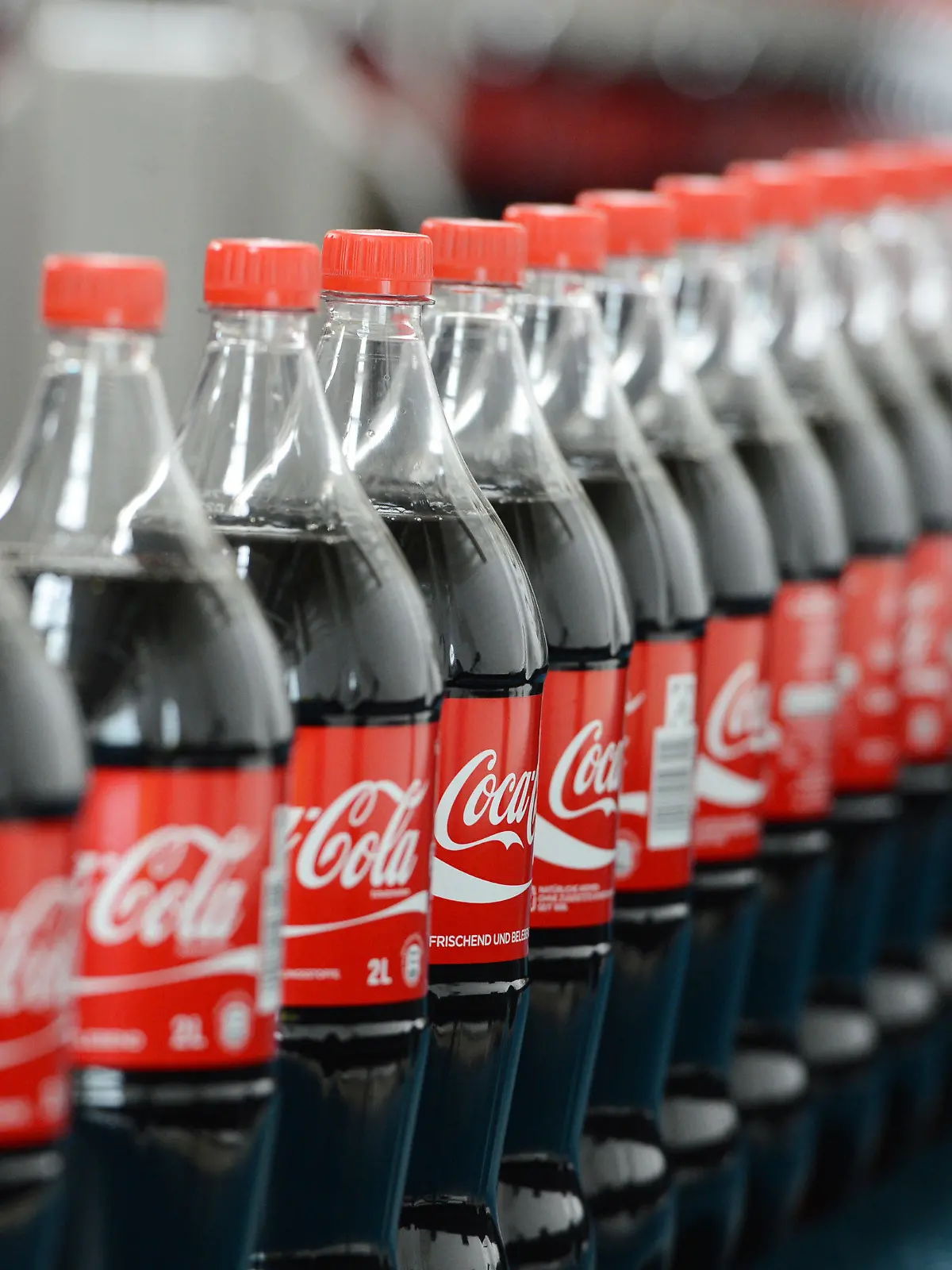 ARCHIV - Zwei-Liter-Getränkeflaschen mit Coca Cola stehen am 21.08.2013 auf einem Transportband. Coca Cola legt am 22.07.2014 in Atlanta, Georgia, USA, die Zahlen für das 2. Quartal vor. Foto: Jens Kalaene/dpa (zu dpa «Coca Cola - 2. Quartal» vom 22.07.2014) +++(c) dpa - Bildfunk+++