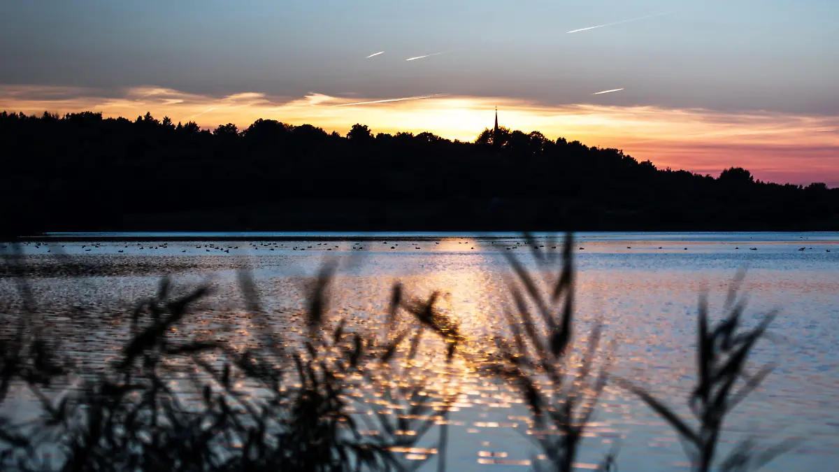 ARCHIV - Die Sonne geht am 02.10.2013 am kleinen Plöner See in Plön (Schleswig-Holstein) unter. Das Umweltministerium, die Wasser- und Bodenverbände sowie die Gemeinden in Schleswig-Holstein unterzeichneten eine Zielvereinbarungen für den besseren Schutz der Gewässer im Land. Foto: Maja Hitij/dpa +++(c) dpa - Bildfunk+++