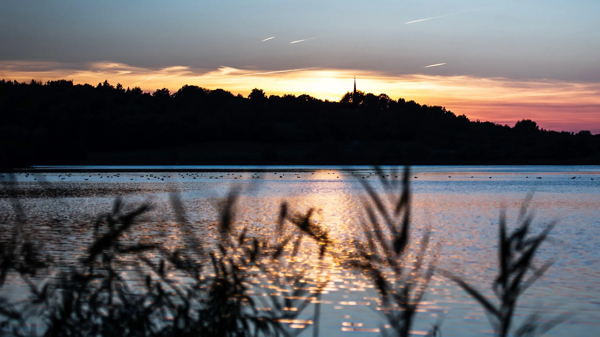 ARCHIV - Die Sonne geht  am 02.10.2013 am kleinen Plöner See in Plön (Schleswig-Holstein) unter. Das Umweltministerium, die Wasser- und Bodenverbände sowie die Gemeinden in Schleswig-Holstein unterzeichneten eine Zielvereinbarungen für den besseren Schutz der Gewässer im Land. Foto: Maja Hitij/dpa +++(c) dpa - Bildfunk+++