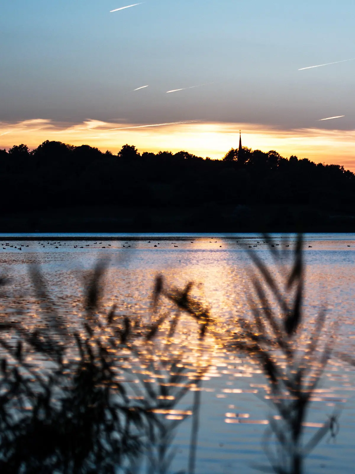 ARCHIV - Die Sonne geht  am 02.10.2013 am kleinen Plöner See in Plön (Schleswig-Holstein) unter. Das Umweltministerium, die Wasser- und Bodenverbände sowie die Gemeinden in Schleswig-Holstein unterzeichneten eine Zielvereinbarungen für den besseren Schutz der Gewässer im Land. Foto: Maja Hitij/dpa +++(c) dpa - Bildfunk+++
