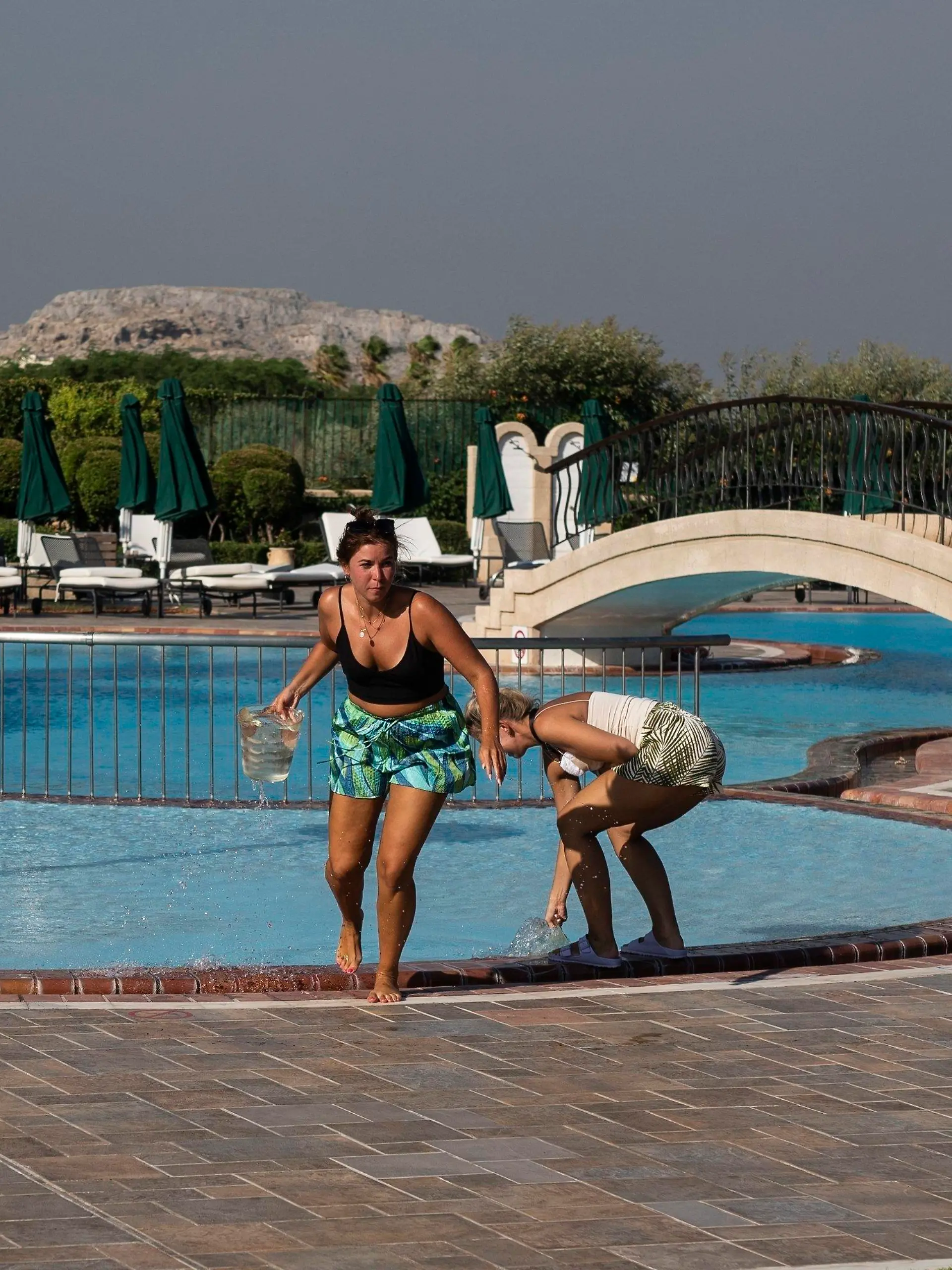 German tourists take water from a swimming pool of a hotel as they try to extinguish a fire near the seaside resort of Lindos, on the Aegean Sea island of Rhodes, southeastern Greece, on Monday, July 24, 2023. A weeklong wildfire on the Greek resort island of Rhodes tore past defenses Monday, forcing more evacuations, as three major fires raged elsewhere in the country fueled by strong winds and successive heat waves that left scrubland and forests tinder-dry. (AP Photo/Petros Giannakouris)