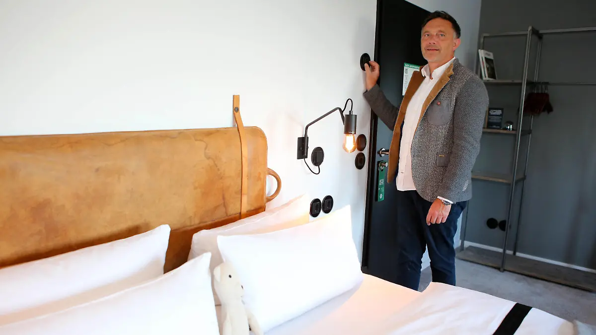 PRODUKTION - 08.08.2022, Niedersachsen, Braunlage: Meik Lindberg, Eigentümer des «The Hearts Hotel», stellt über ein Regelsystem die Temperatur in einem Hotelzimmer ein. Das Hotel kann die Ober- und Untergrenze der Temperatur zentral steuern. (zu dpa: «Pool, Heizung, Küche: Gastgewerbe sucht nach Energiesparmöglichkeiten») Foto: Stefan Rampfel/dpa +++ dpa-Bildfunk +++