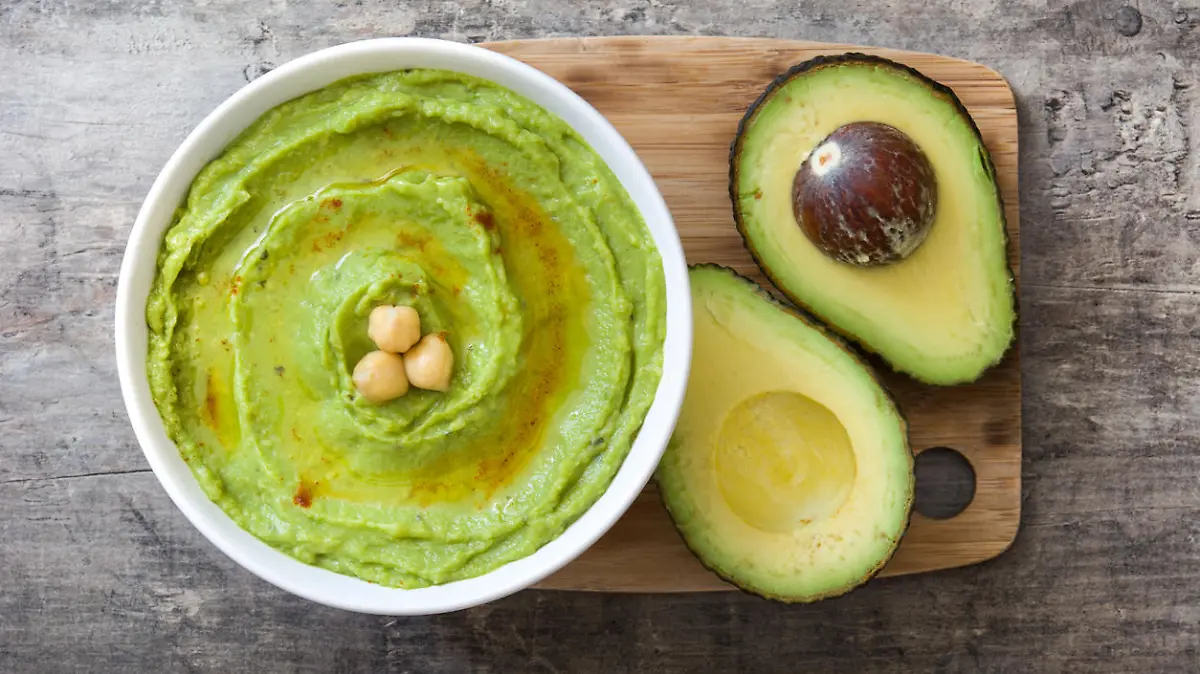 Avocado hummus in bowl on wooden background
