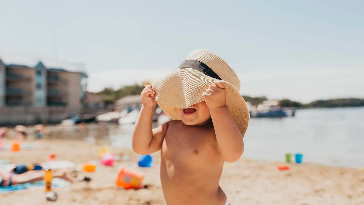 Toddler Boy Playing Peek-a-boo with Sun Hat on Beach Milwaukee, WI, United States PUBLICATIONxINxGERxSUIxAUTxONLY CRSUWE200424C-371586-01,model released, Symbolfoto