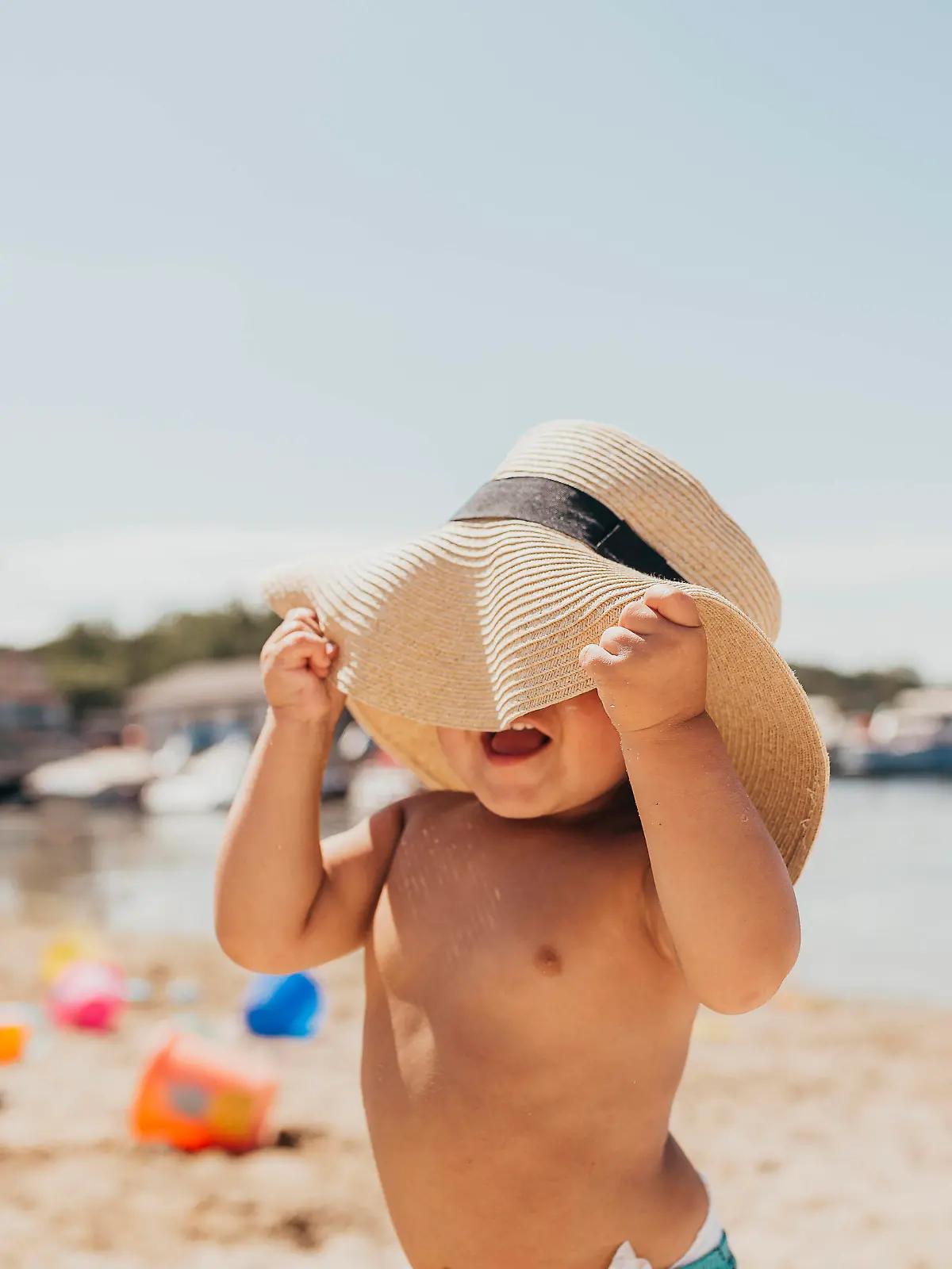 Toddler Boy Playing Peek-a-boo with Sun Hat on Beach Milwaukee, WI, United States PUBLICATIONxINxGERxSUIxAUTxONLY CRSUWE200424C-371586-01,model released, Symbolfoto