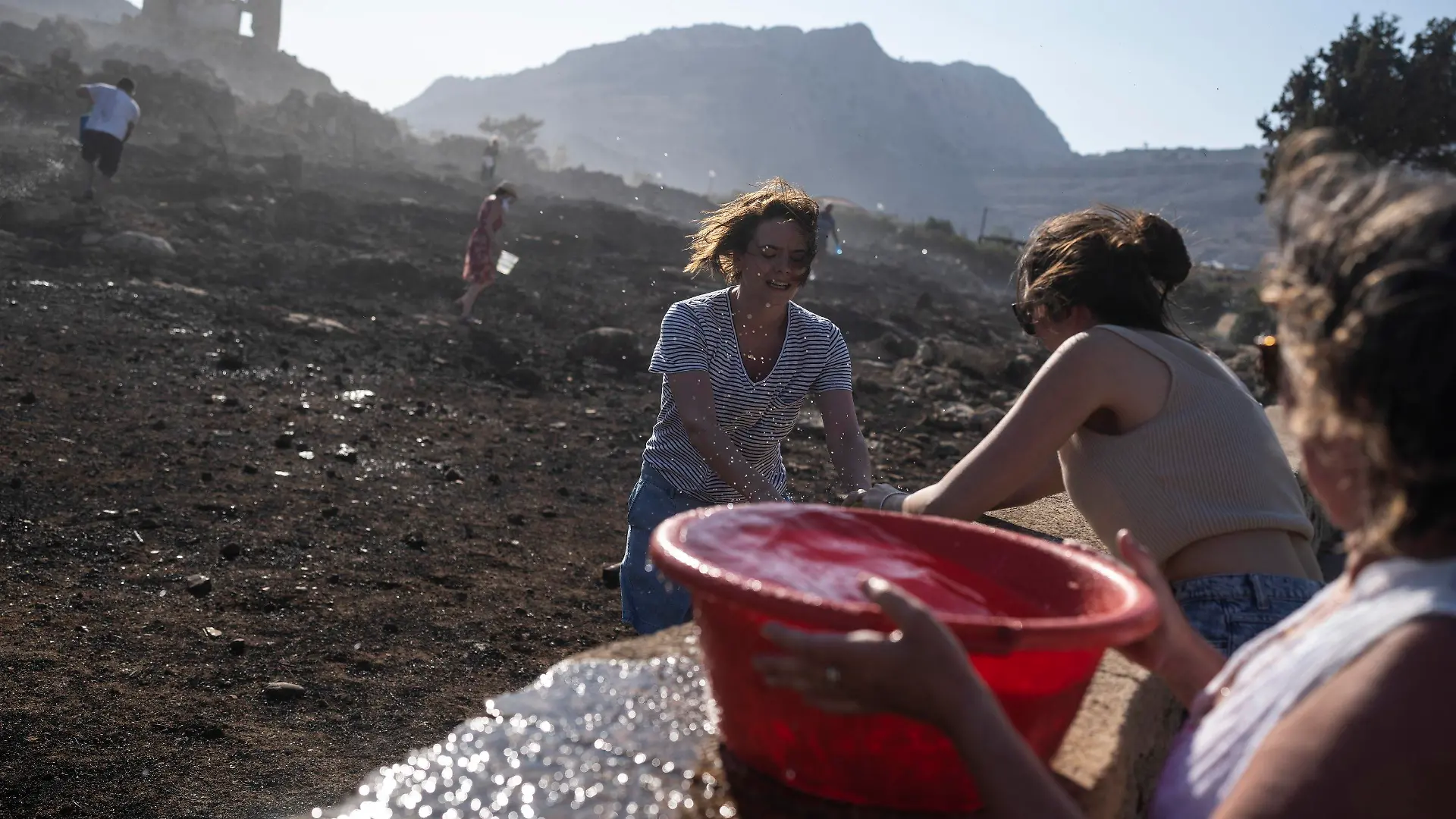 German tourists together with local residents try to extinguish a fire, near the seaside resort of Lindos, on the Aegean Sea island of Rhodes, southeastern Greece, on Monday, July 24, 2023. A weeklong wildfire on the Greek resort island of Rhodes tore past defenses Monday, forcing more evacuations, as three major fires raged elsewhere in the country fueled by strong winds and successive heat waves that left scrubland and forests tinder-dry. (AP Photo/Petros Giannakouris)
