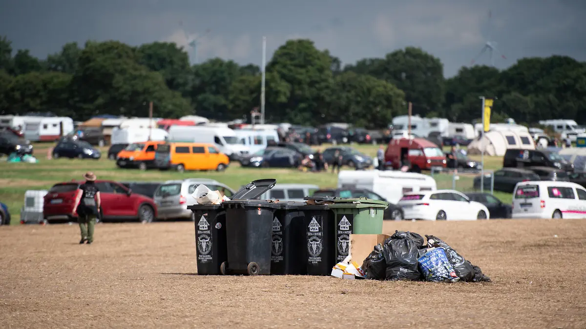 07.08.2022, Schleswig-Holstein, Wacken: Zurückgelassener Müll liegt auf dem Wacken Open Air Festival rund um Mülltonnen. Die 31. Auflage des Heavy-Metal-Festivals ist in der Nacht zum Sonntag zu Ende gegangen. Foto: Daniel Reinhardt/dpa +++ dpa-Bildfunk +++