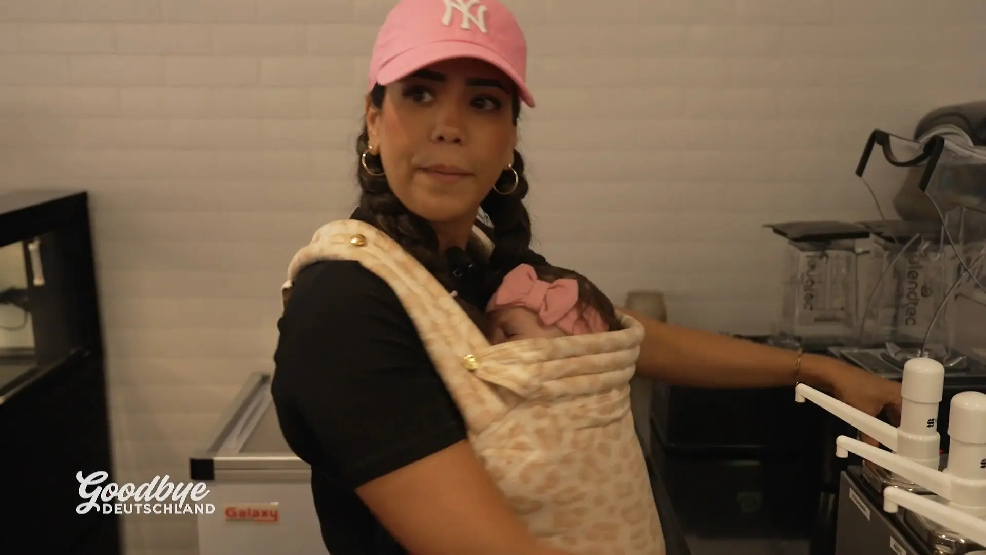 Aicha arbeitet mit Baby Lana auf dem Arm Smoothieladen