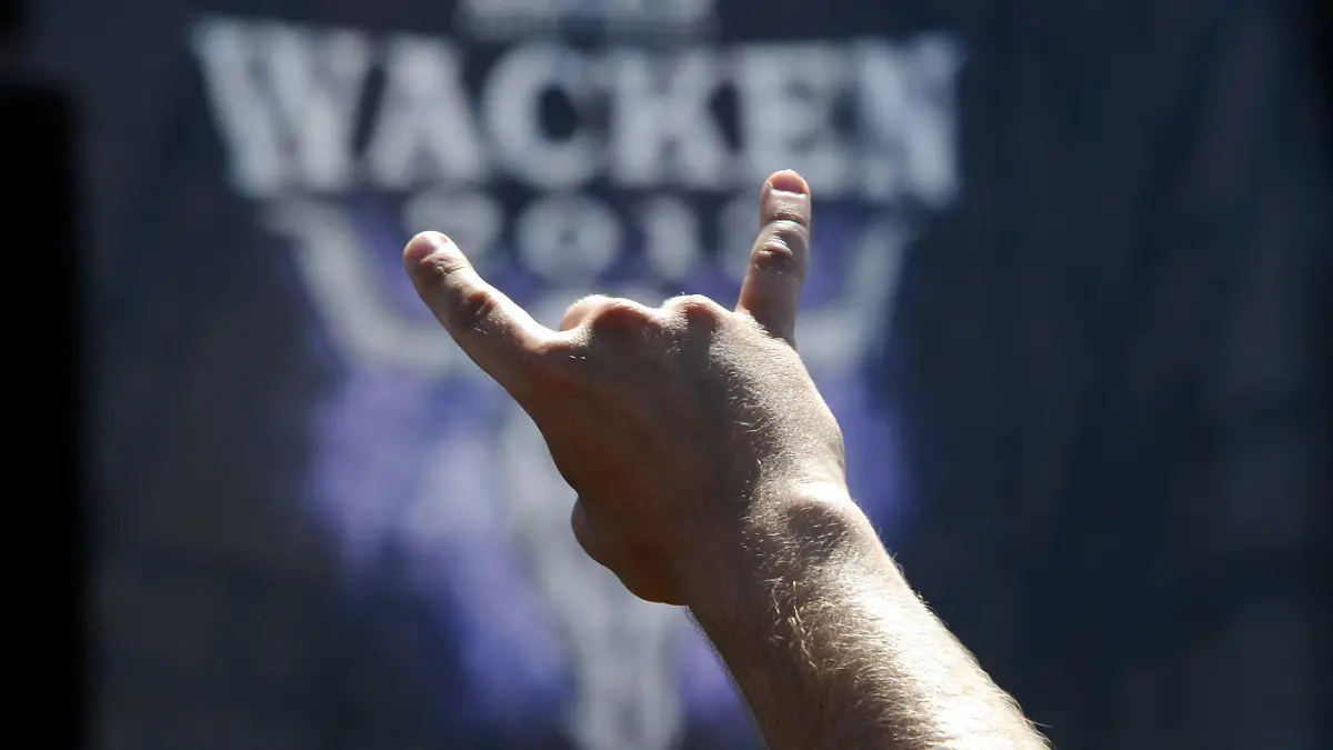 ARCHIV - 02.08.2013, Schleswig-Holstein, Wacken: Ein Festivalbesucher zeigt auf dem Festivalgelände in Wacken das Zeichen der Heavy-Metal-Fans, die «Pommesgabel». Wegen der Corona-Pandemie fällt das weltbekannte Heavy-Metal-Festival erstmals in 30 Jahren aus. (zu dpa "30 Jahre Heavy-Metal-Festival in Wacken") Foto: Carsten Rehder/dpa +++ dpa-Bildfunk +++