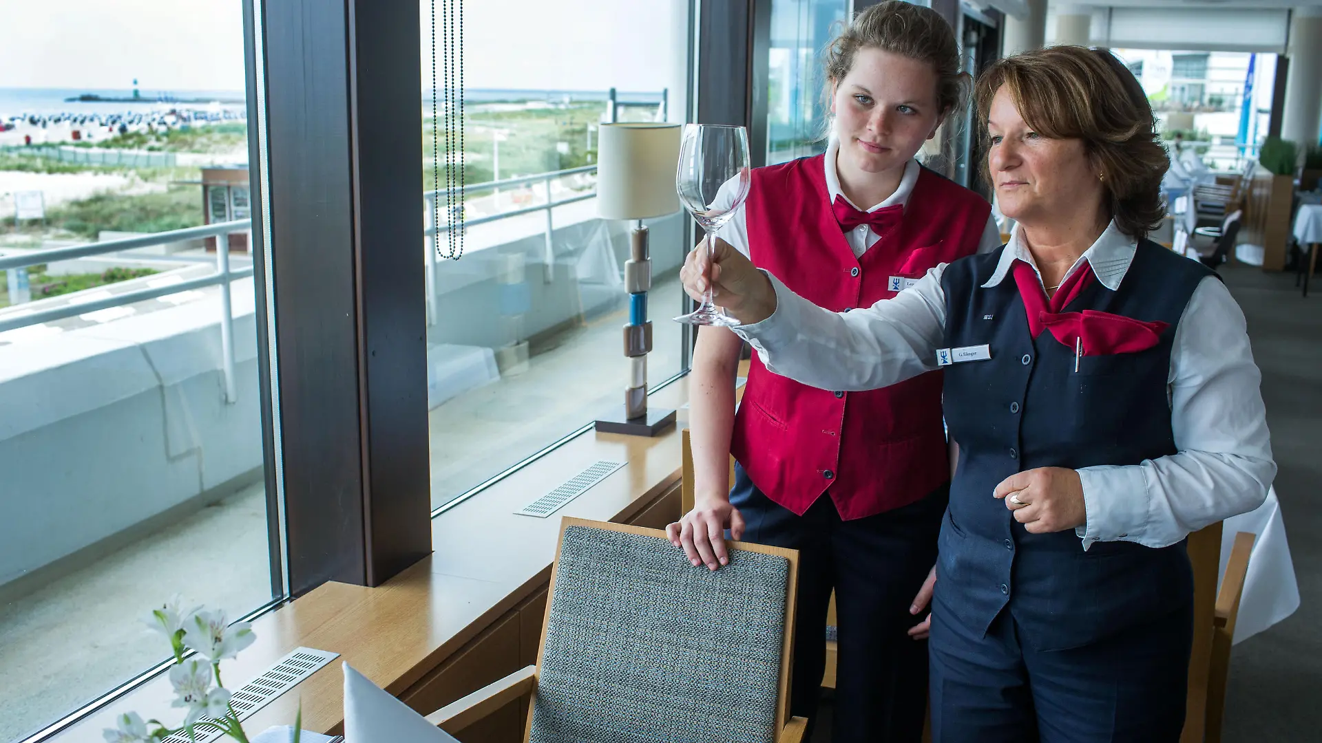 Schülerpraktikantin Lena Marie Dinse (l) aus der zehnten Klasse des Mittelstädtischen Gymnasiums Rostock deckt am 25.06.2015 im Hotel Neptun in Rostock-Warnemünde (Mecklenburg-Vorpommern) mit Restaurantfachfrau Gerlinde Illinger einen Tisch ein. Ferienjobs als Hotelpagen, Eisverkäufer oder Zimmermädchen im Fünf-Sterne-Haus sind bei Schülern so beliebt, dass die Stellen rund ein Jahr im voraus vergeben sind. Eine Internet-Plattform will nun vermitteln. Foto: Jens Büttner/dpa (zu dpa-Korr _Koffer tragen, Kühe hüten - Ferienjobs sind heiß begehrt" vom 27.06.2015) ++