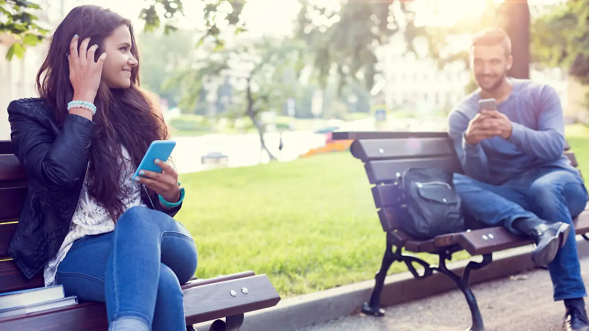 Happy couple using smartphones in the city park