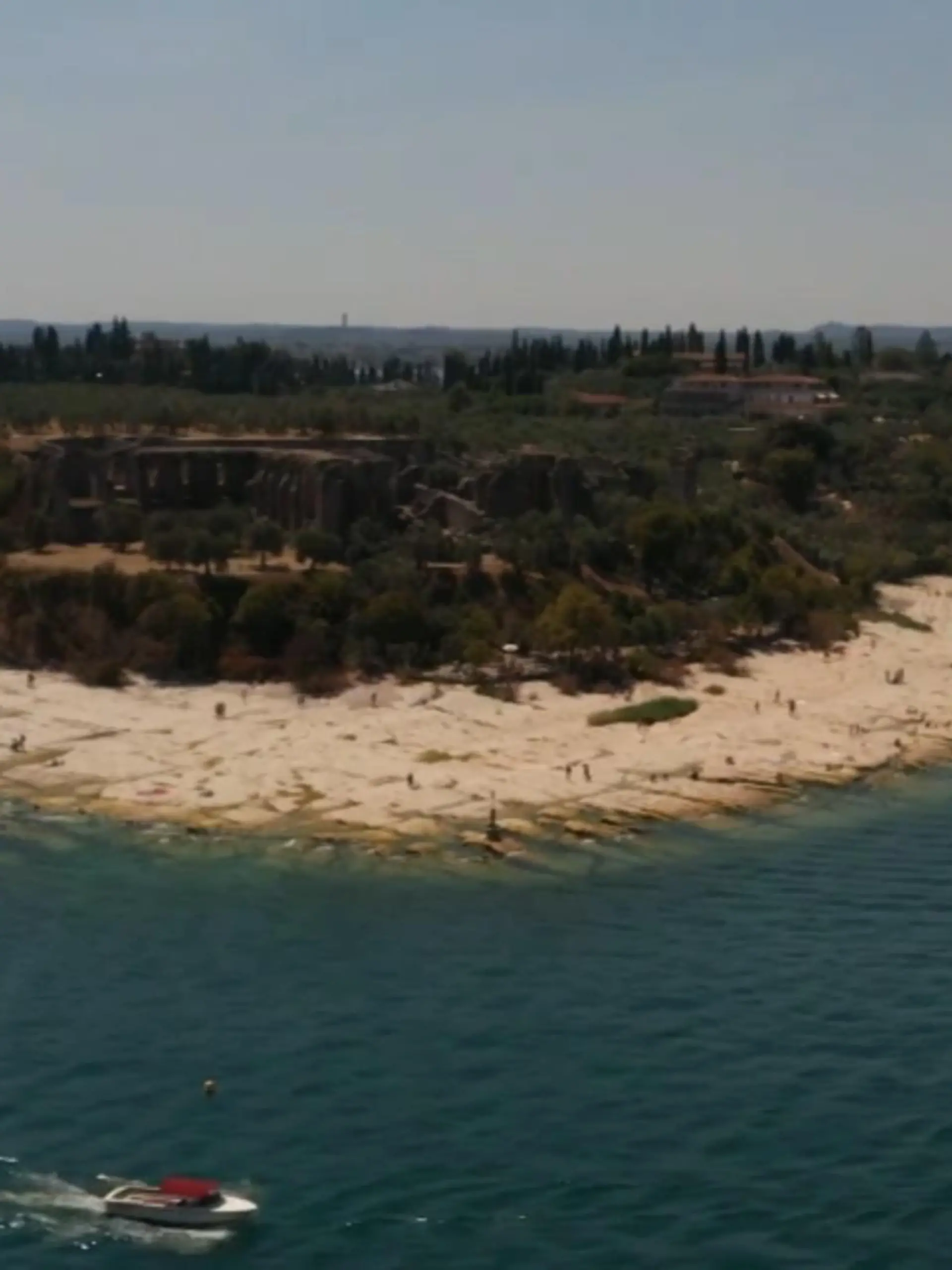Der Gardasee in Italien fasst historisch wenig Wasser. Aufgrund der andauernden Hitze fließt zu wenig Wasser in den umliegenden Flüssen. Also wird Wasser unter anderem aus dem Gardasee abgepumpt. Das geht nicht spurlos an dem beliebten Badeort vorbei. Die Touristen interessiert es herzlich wenig.