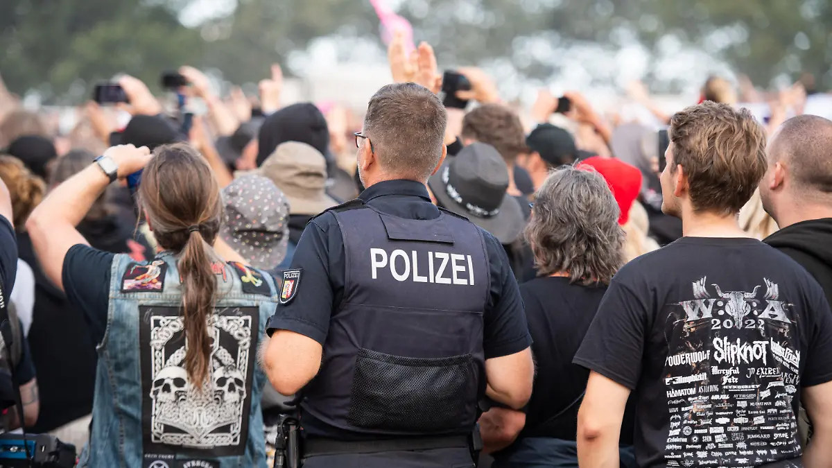 06.08.2022, Schleswig-Holstein, Wacken: Ein Polizist steht beim Wacken Open Air Festival im Publikum. Das WOA gilt als größtes Heavy-Metal-Festival der Welt. Foto: Daniel Reinhardt/dpa +++ dpa-Bildfunk +++