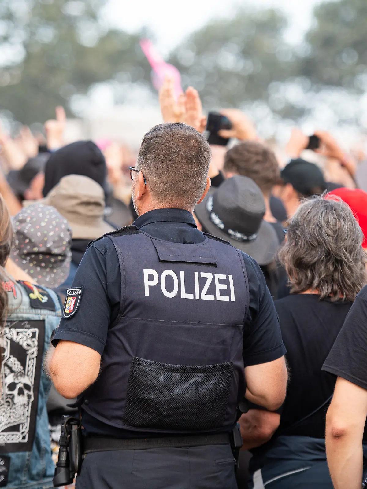 06.08.2022, Schleswig-Holstein, Wacken: Ein Polizist steht beim Wacken Open Air Festival im Publikum. Das WOA gilt als größtes Heavy-Metal-Festival der Welt. Foto: Daniel Reinhardt/dpa +++ dpa-Bildfunk +++