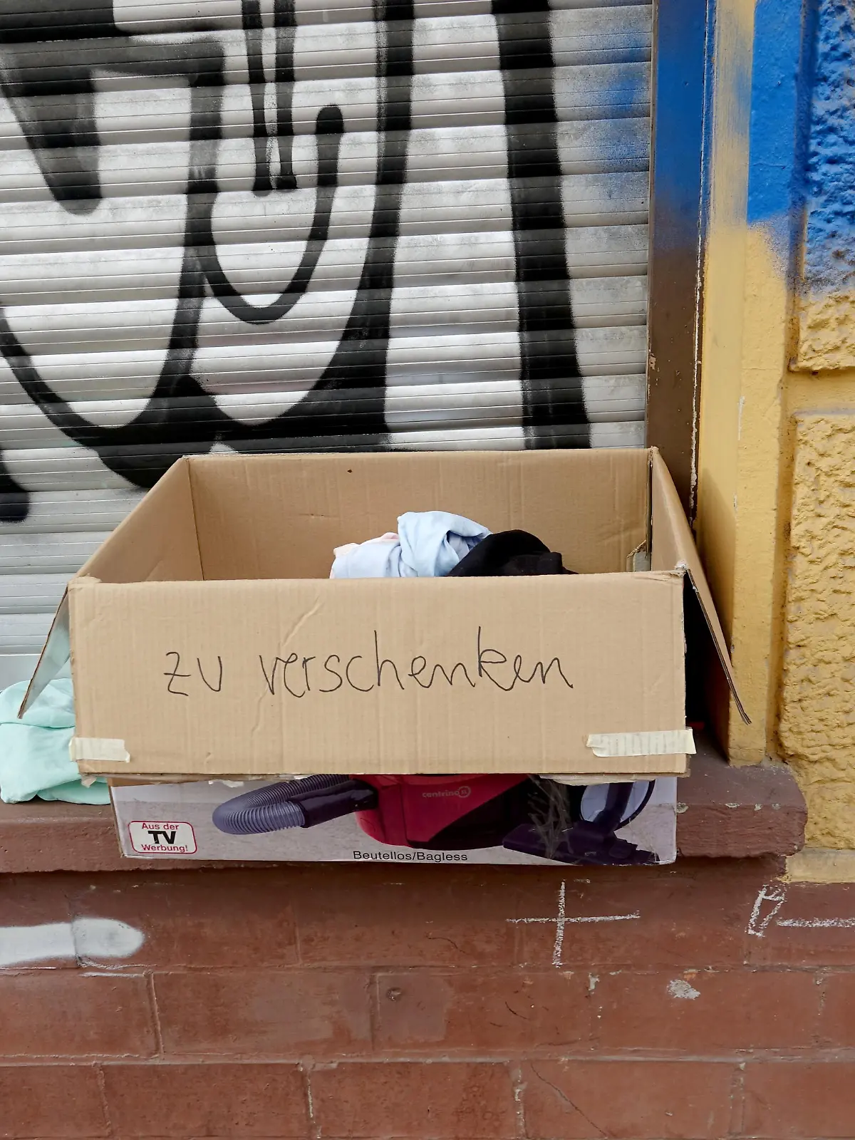«Zu verschenken» steht auf einem Karton mit Kleidern, der auf einer Fensterbank steht.