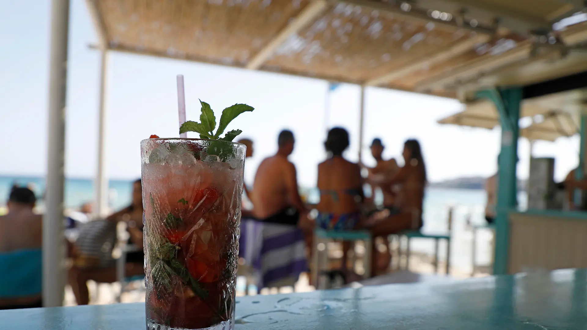 Menschen sitzen in einer Bar am Strand von Cala Major, in der Nähe von Palma auf Mallorca. Im Vordergrund steht ein Drink - ein Mojito. Auf der spanischen Urlaubsinsel sind in diesen Tagen nicht nur der Sand und die Luft sehr heiß, sondern auch das Meereswasser erreicht ungewöhnlich hohe Temperaturen. (zu dpa Hitze auf Mallorca - Meer vor dem «Ballermann» wird zur warmen Brühe)